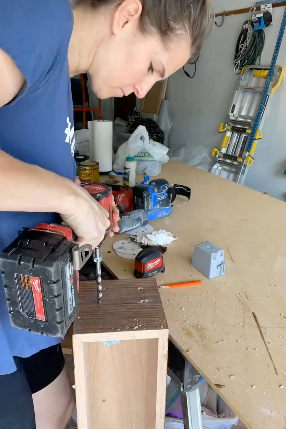 Tracing an electrical box outline on a DIY fireplace mantel to prepare for outlet installation.